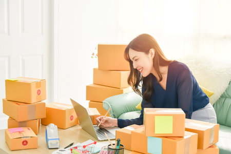 Female startup small business owner working with notebook computer at home. Online selling. E-commerce.の写真素材