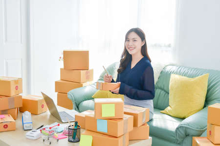 Female startup small business owner working with notebook computer at home. Online selling. E-commerce.の写真素材