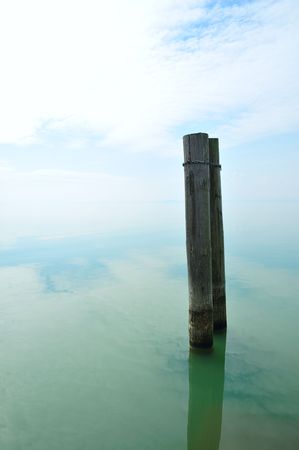 Two poles in a calm, cloudy lakescapeの写真素材