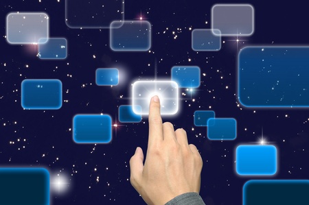 hand pushing a button on a touch screen interface under starry night skyの写真素材