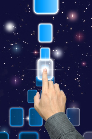 hand pushing a button on a touch screen interface under starry night skyの写真素材