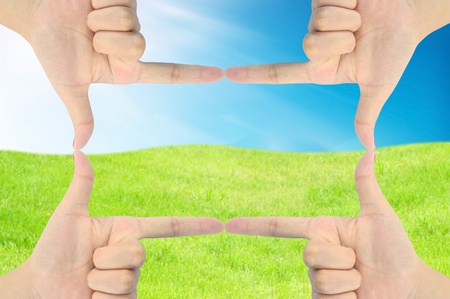 hand as frame on fresh grass and blue skyの写真素材
