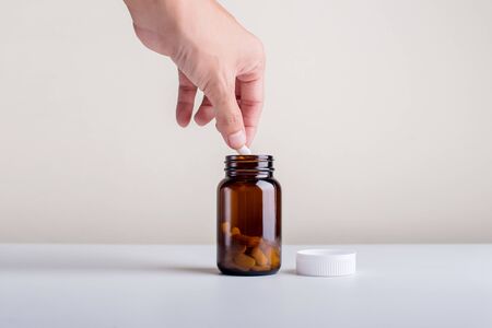 The hand that is picking the supplement out of the bottle on a white background.Dietary supplement product.の写真素材