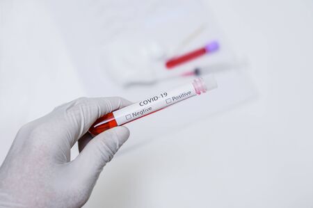 Wear protective gloves. Holding a blood collection tube COVID-19. Blur the white background and dressings.の写真素材