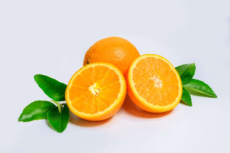 Two fresh orange slices and one orange fruit with green leaf isolated on white background.の写真素材