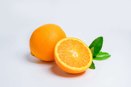 Two fresh orange slices and one orange fruit with green leaf isolated on white background.の写真素材