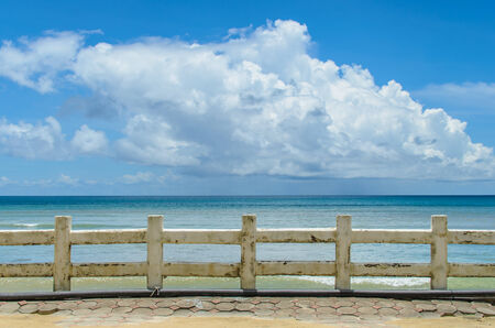 Cement fence on the sea on a background of blue sky with cloudsの写真素材