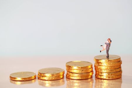 Miniature people: couple standing on stacking golden coins, saving and investment concept using as backgroundの写真素材