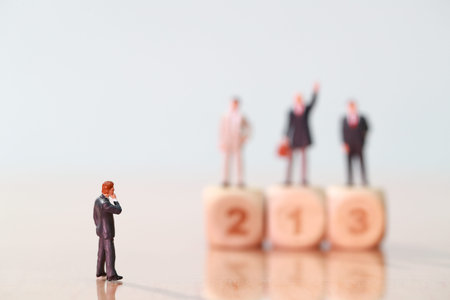 Miniature people: businessman looking and thinking at competitor standing on wooden podium (Financial and Business competition concept)の写真素材