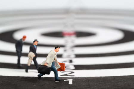 Miniature people: businessman running to dartboard target center idea of competition and business...