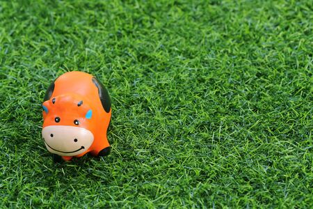 cute toy cow on grass, using as backgroundの写真素材