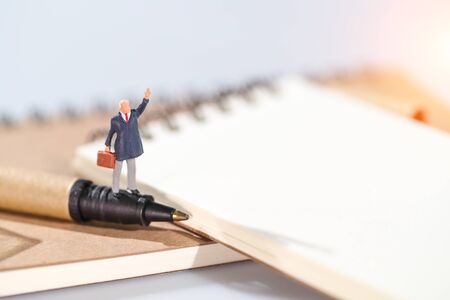 Miniature people: businessman standing on blank notebook idea of financial and business goalの写真素材