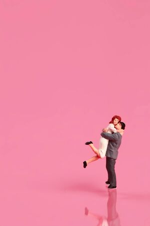 Miniature people: a couple standing on pink background idea for love conceptの写真素材