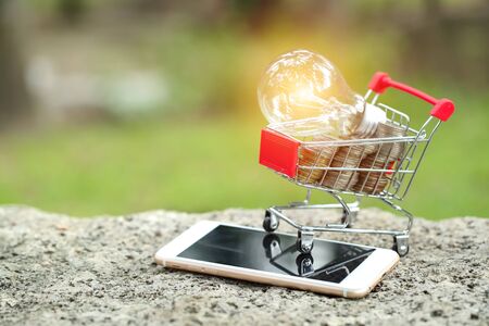 trolley with coins, cell phone and electric glass bulb, idea for shopping and online payment using as business backgroundの写真素材
