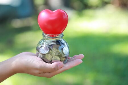 human hand saving money on red heartの写真素材