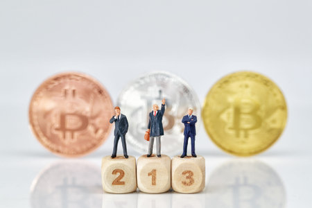 Miniature people: businessman standing on wooden podium with bitcoins blur background (Financial and...