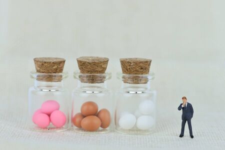 miniature businessman is looking at easter eggs. how to do business with easter eggs?の写真素材
