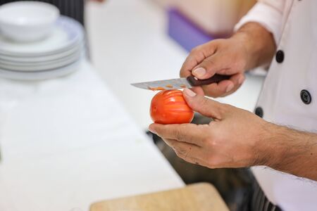 male chef hand using knife and cooking tomato in restaurantの写真素材
