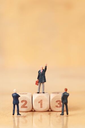 Miniature people: businessman standing with wooden podium using as background (Financial and Business competition concept)の写真素材