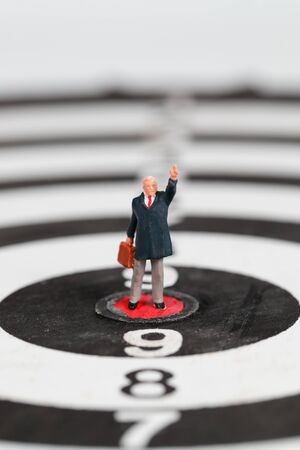 Miniature people: businessman standing on dartboard target center idea of financial and business goalの写真素材