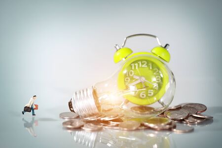 Miniature people: businessman walking beside money and electric glass bulb, idea for financial and Business competition conceptの写真素材