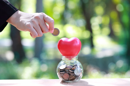 human hands saving money with red heart symbol sign