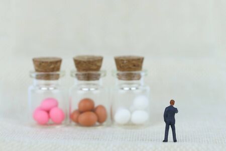miniature businessman is looking at easter eggs. how to do business with easter eggs?の写真素材