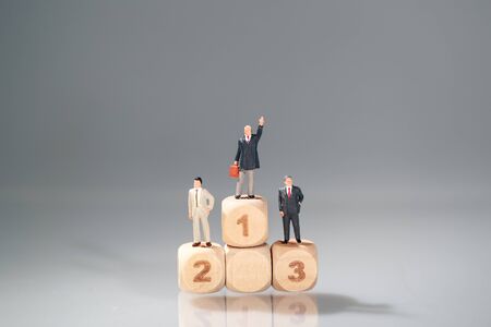 Miniature people: businessman standing on wooden podium (Financial and Business competition concept)の写真素材