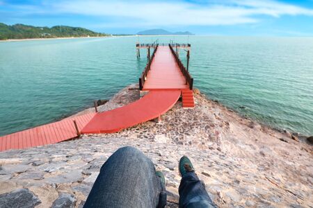 top view portrait of man legs enjoy holiday vacation and wearing jean and sneakers with red bridge and blue skyの写真素材