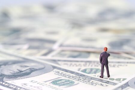 Miniature people: businessman standing and thinking on banknotes (Financial and Business competition concept)の写真素材