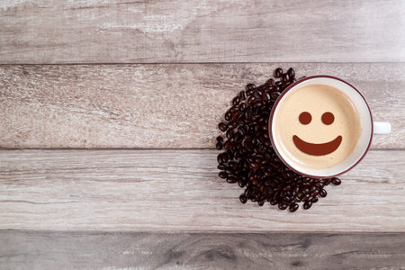 coffee cup with smiling face and bean on wooden tableの写真素材