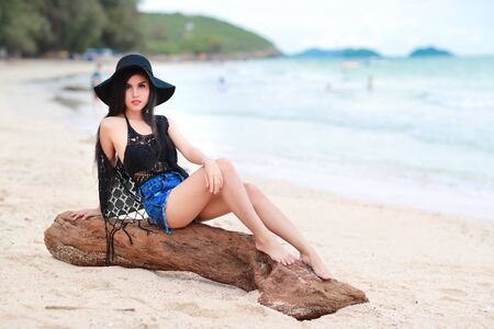 portrait of fashion and beautiful girl with black hat on the beachの写真素材
