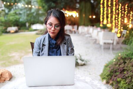 cute and charming businesswoman with glasses working on laptop computer from restaurant or cafeの写真素材