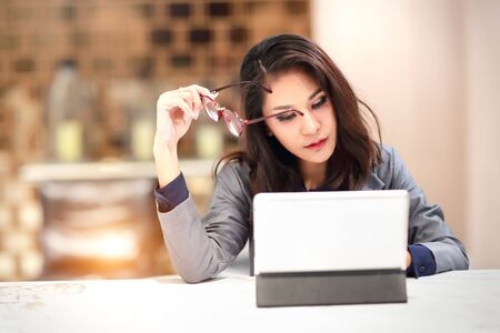 working and charming woman with glasses using tablet (work from home concept)の写真素材