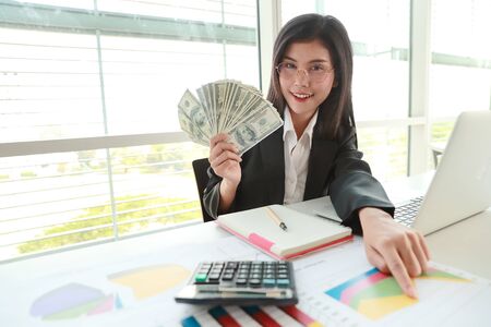 businesswoman showing company summary report and graph with money on handsの写真素材