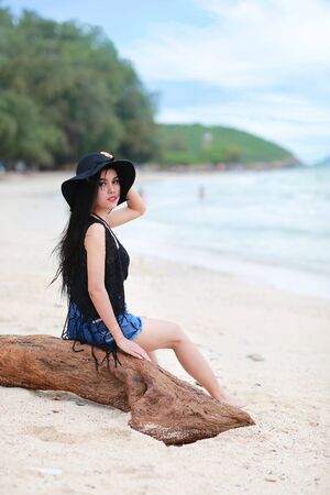 portrait of fashion and beautiful girl with black hat on the beachの写真素材