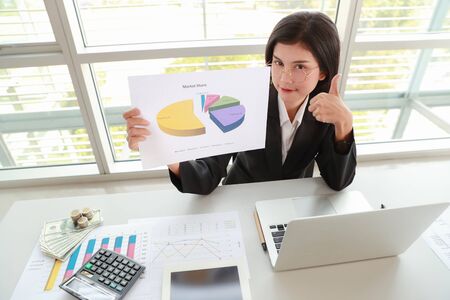 businesswoman showing thumb up and company profit with graph in meeting roomの写真素材