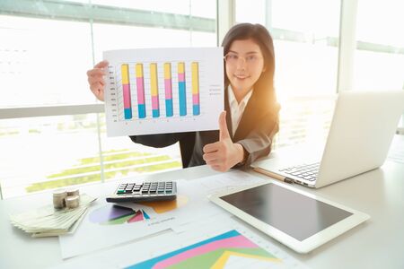 businesswoman showing thumb up and company profit with graph in meeting roomの写真素材