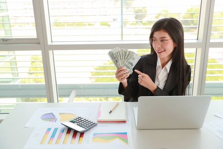 businesswoman showing company summary report and graph with money on handsの写真素材