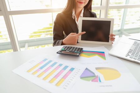businesswoman showing blank screen tablet with computer on tableの写真素材