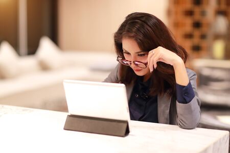 working and charming woman with glasses using tablet (work from home concept)の写真素材