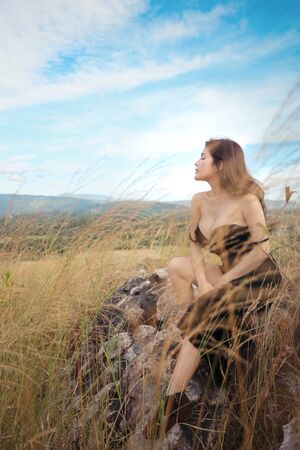 portrait of young and beautiful woman having a happy time and enjoying among grass field on the mountain in natureの写真素材