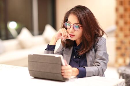 working and charming woman with glasses using tablet (work from home concept)の写真素材