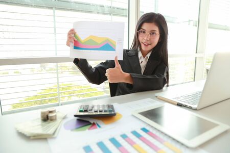 businesswoman showing thumb up and company profit with graph in meeting roomの写真素材