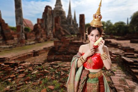 fashion asian girl in Thai traditional costume in ancient temple with steering wheel flower in handの写真素材