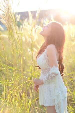 portrait of beautiful woman having a happy time and enjoying among grass field in natureの写真素材
