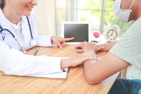 doctor comforting , showing something on tablet and holding hand male patient with care (medical concept)の写真素材