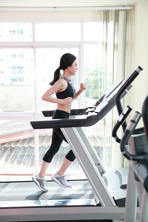 young healthy sport woman running or walking on exercise machine in gym (workout concept)