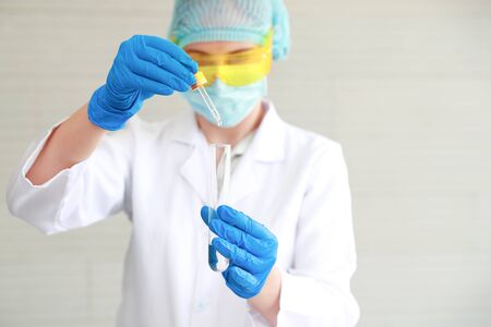 scientist woman with equipment and laboratory glassware holding chemical liquid and checking result using as science research backgroundの写真素材