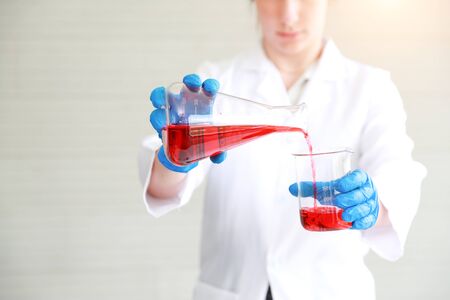 scientist woman with equipment and laboratory glassware holding chemical liquid and checking result using as science research backgroundの写真素材